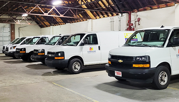 six white delivery vans parked in warehouse
